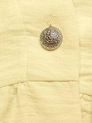 Yellow peplum hem two-piece set detail with textured silver button.