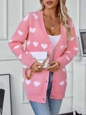 Blush pink acrylic knit cardigan with white heart pattern and button front.