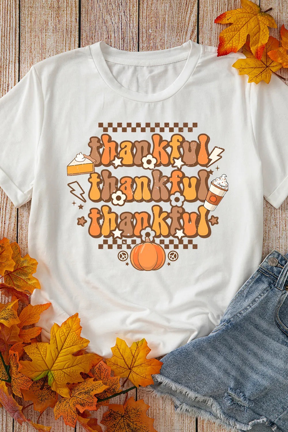 White graphic tee with "thankful" repeated in groovy font, pumpkin, pie, and coffee cup graphics.