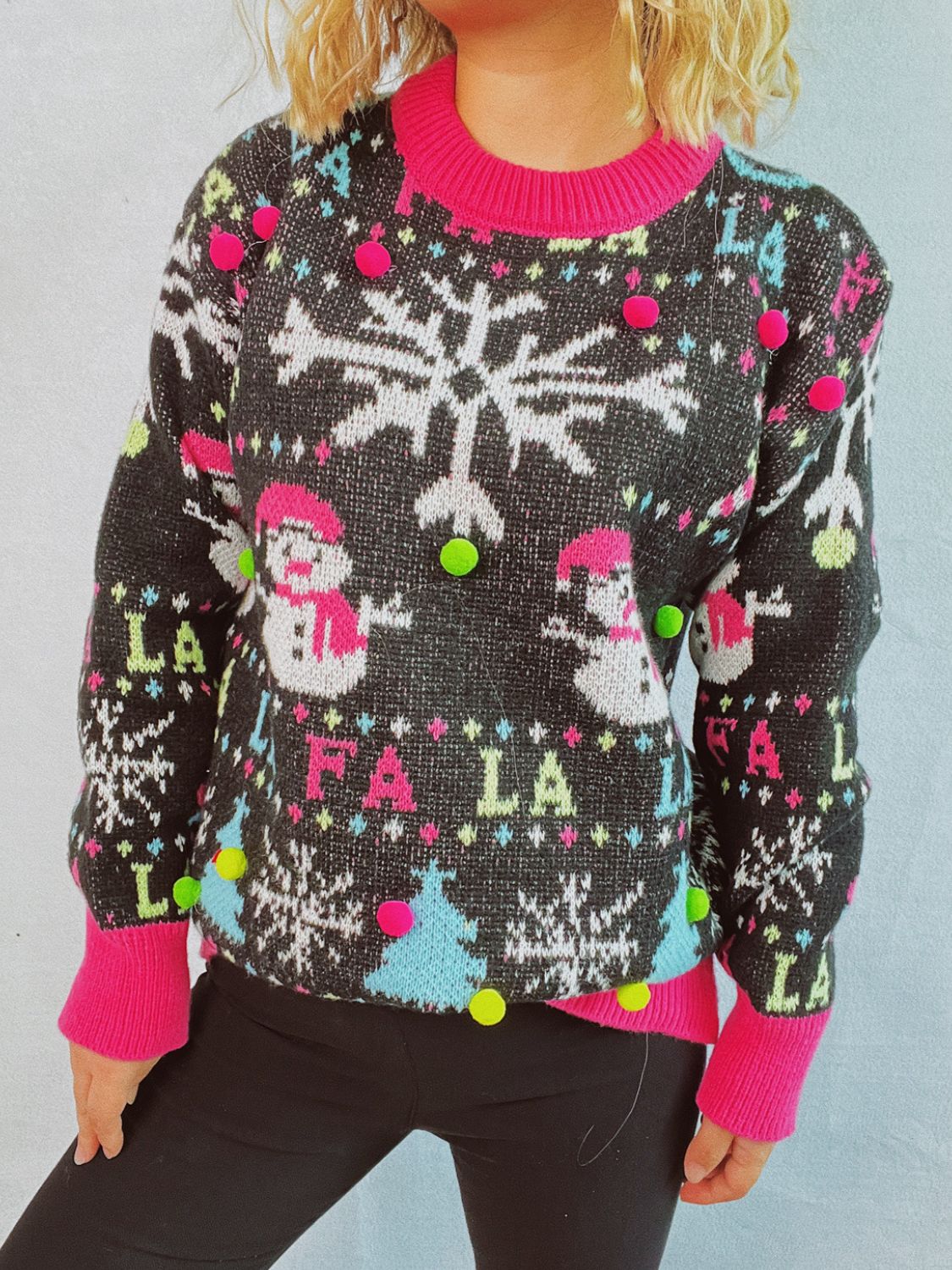 Black knit sweater with snowmen, snowflakes, trees, and pom-pom embellishments.