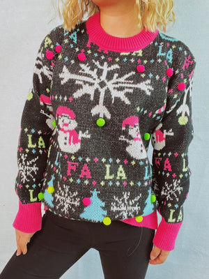 Black knit sweater with snowmen, snowflakes, trees, and pom-pom embellishments.