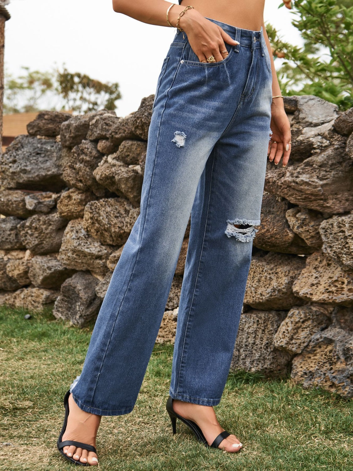 Distressed blue denim flare jeans with ripped details and frayed hem.