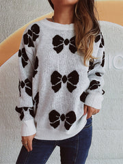 White acrylic sweater with black bow print, crew neck, relaxed fit, and ribbed cuffs.