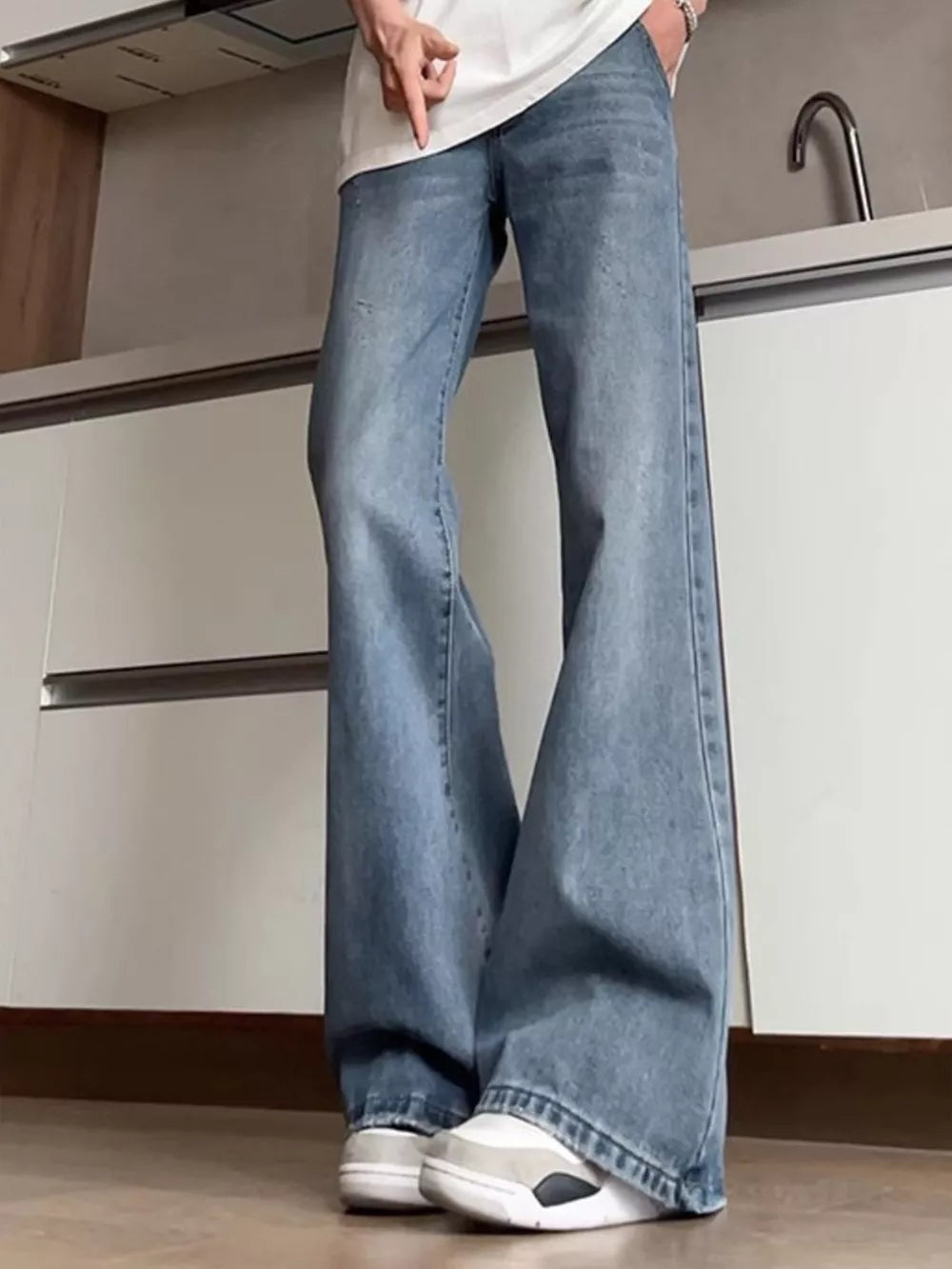 Men's distressed full-length flare jeans in light blue cotton blend with subtle rips.