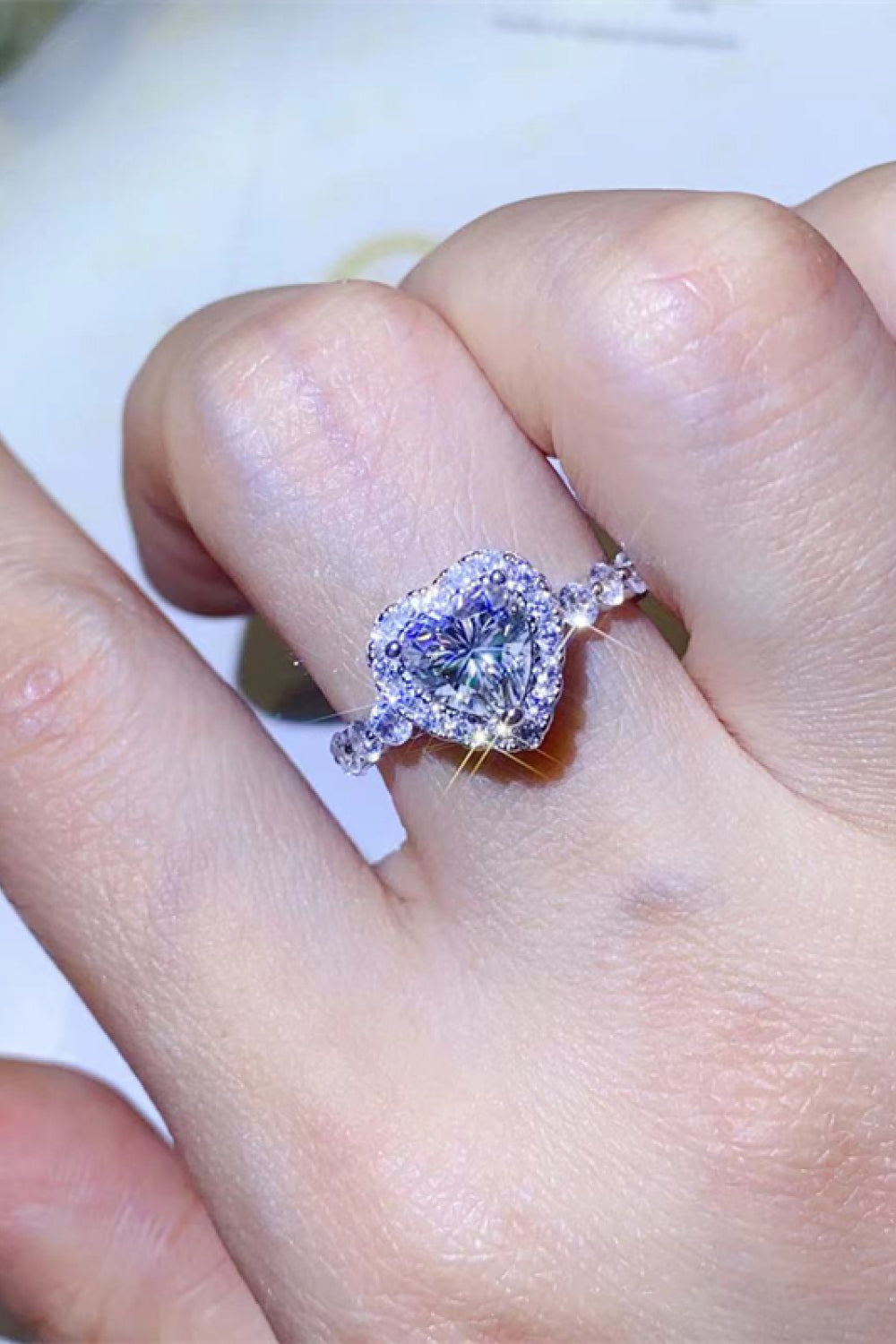 White moissanite halo engagement ring with heart-shaped center stone.