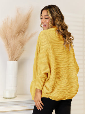 Gold acrylic knit cocoon cardigan with pockets and cuffed sleeves.