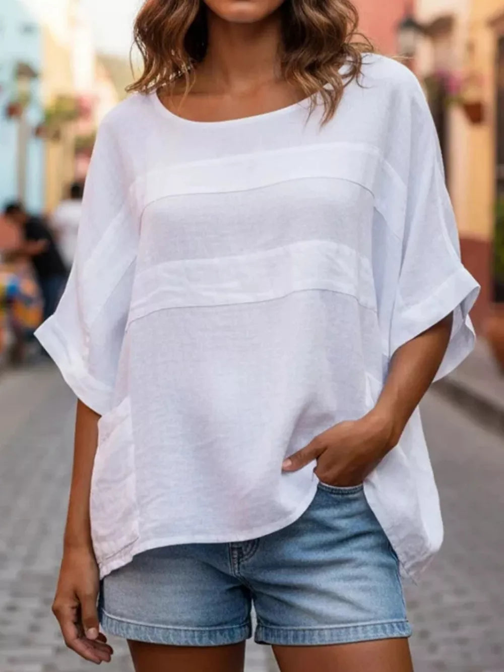 White relaxed fit blouse with horizontal textured stripes and short sleeves, paired with denim shorts.