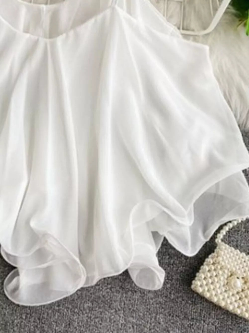 White ruffled camisole with spaghetti straps and delicate sheer layers.