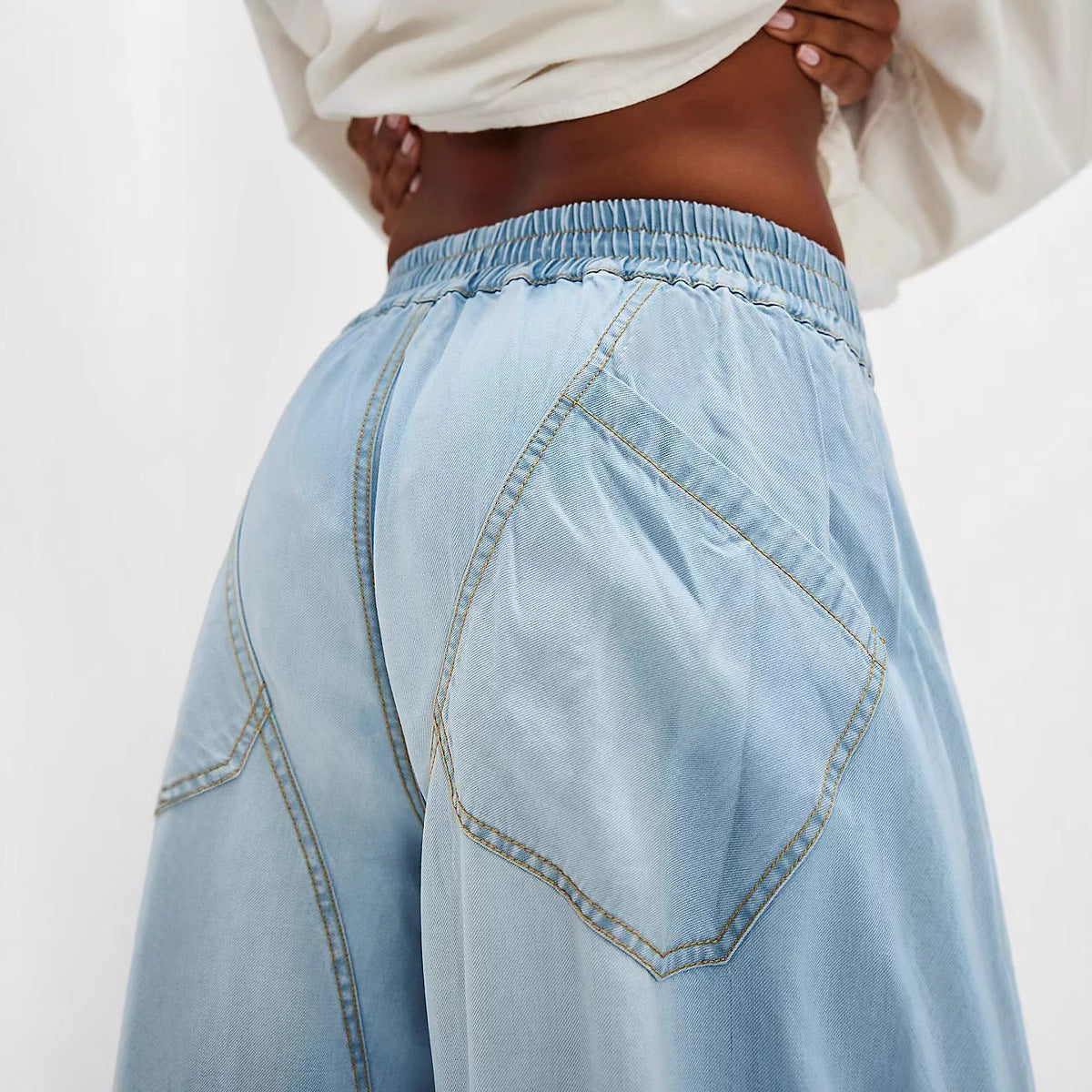 Light blue denim jeans with elastic waistband and unique pocket stitching detail.