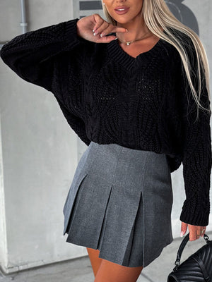 Black cable knit V-neck sweater with relaxed fit and long sleeves.
