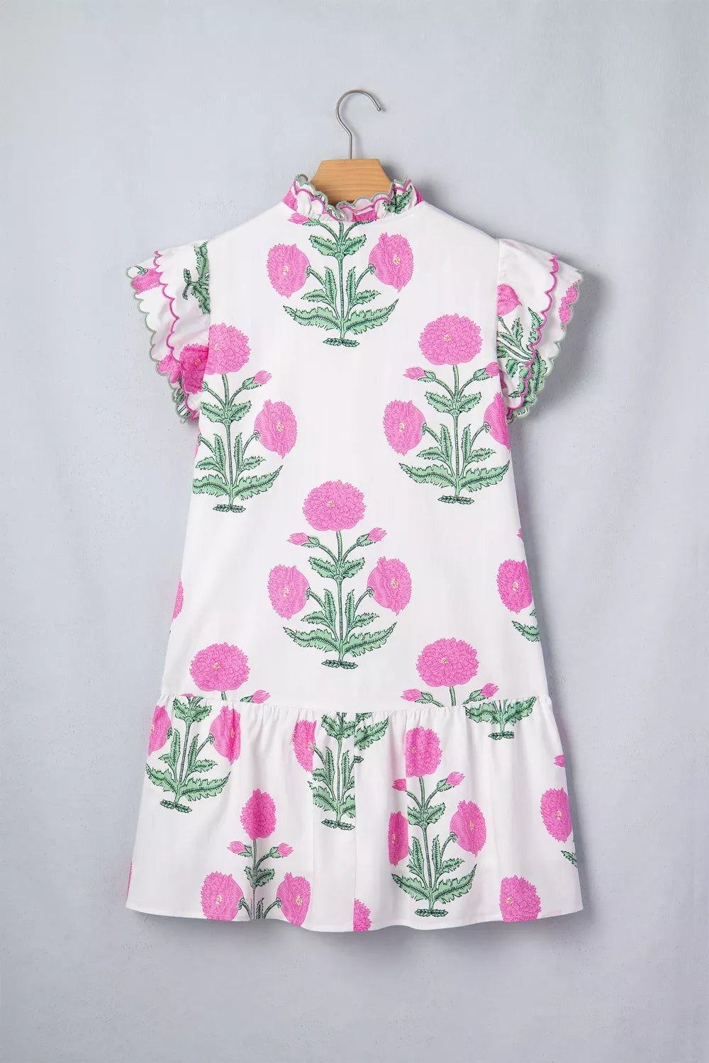White mini dress with pink floral print, ruffled neckline, and scalloped flutter sleeves.