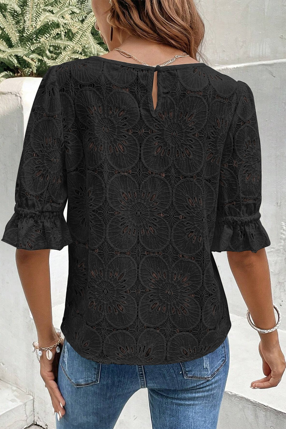 Black lace blouse with eyelet floral pattern, puff sleeves and ruffled cuffs.