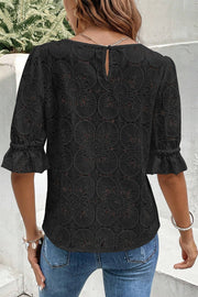Black lace blouse with eyelet floral pattern, puff sleeves and ruffled cuffs.