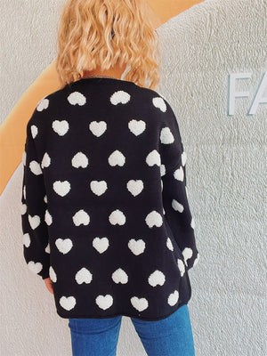 Black acrylic cardigan with white textured heart motif pattern, crew neck, long sleeves.