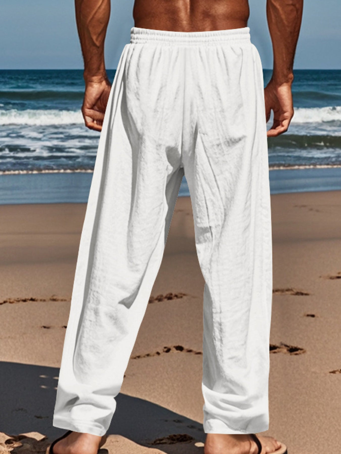 White relaxed fit drawstring sweatpants with button-fly, cotton blend, on a man at the beach.