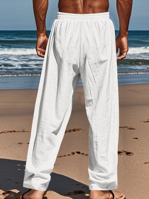 White relaxed fit drawstring sweatpants with button-fly, cotton blend, on a man at the beach.