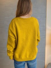 Mustard yellow acrylic oversized knit cardigan with crew neck and long sleeves.