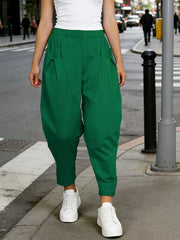 Dark green harem pants with pockets and vertical texture, cropped length.