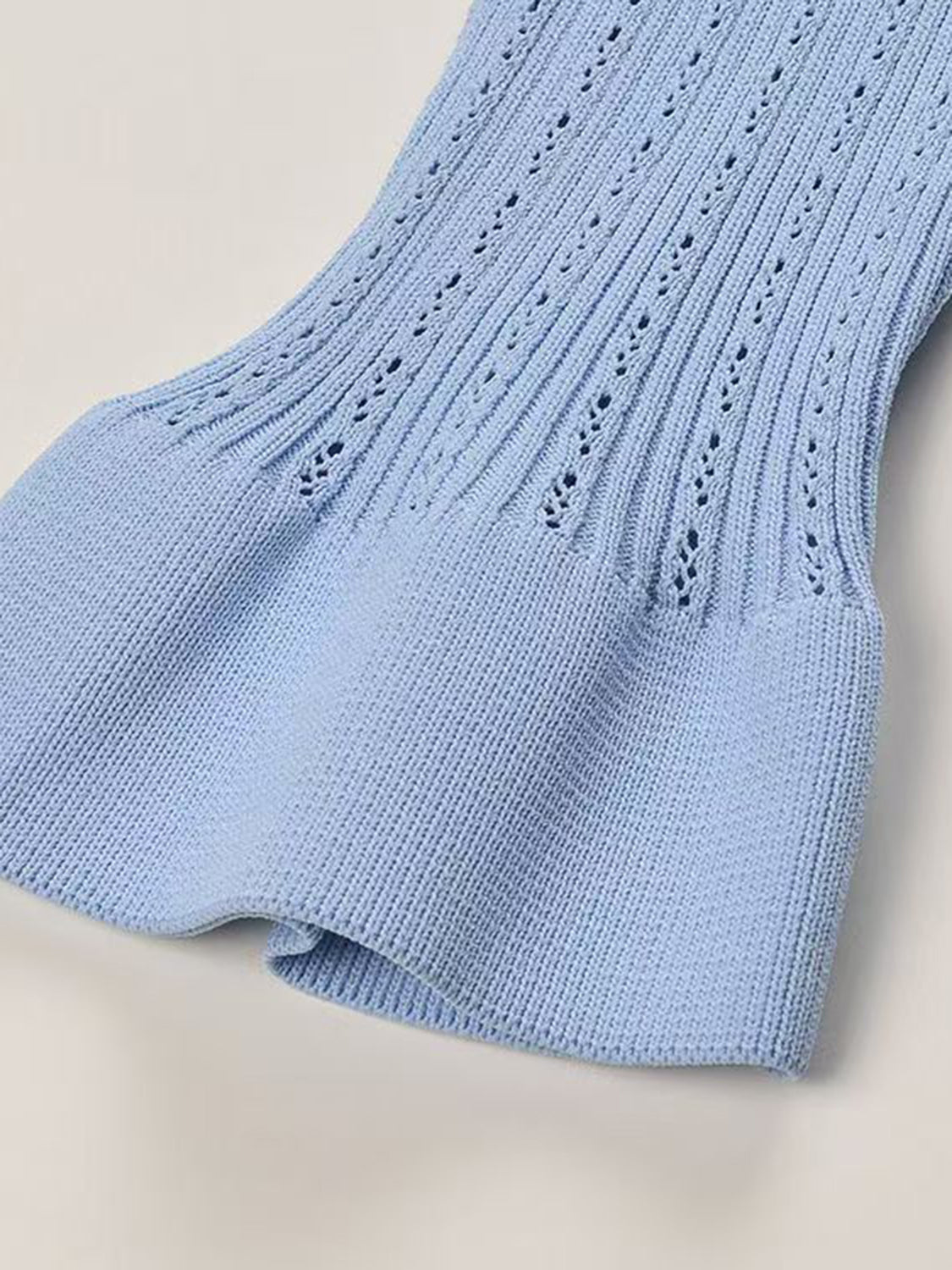 Light blue knit cardigan with openwork detail and ruffled hem.