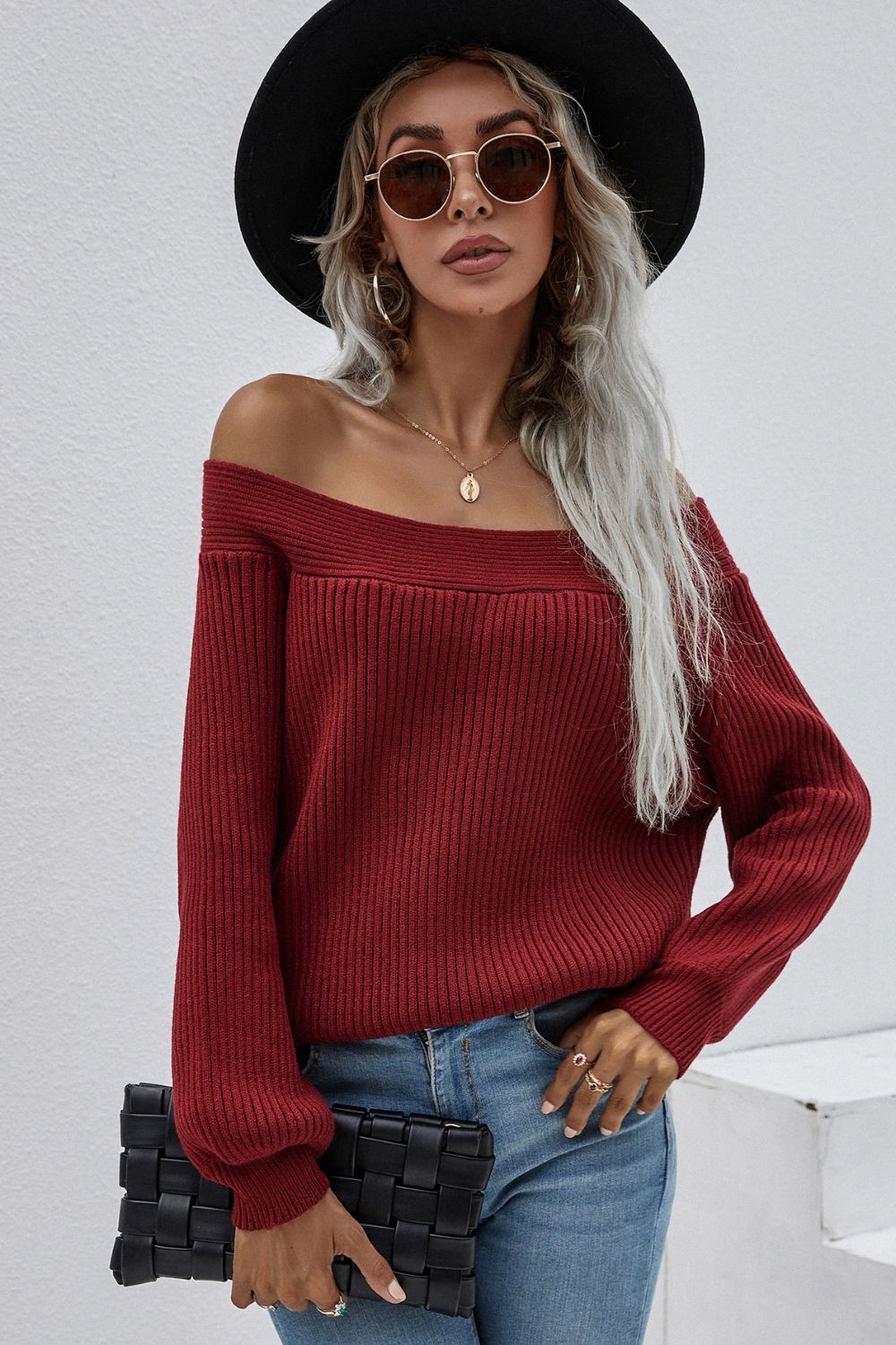 Red ribbed knit sweater with boatneck and puff sleeves, styled with jeans and a clutch.