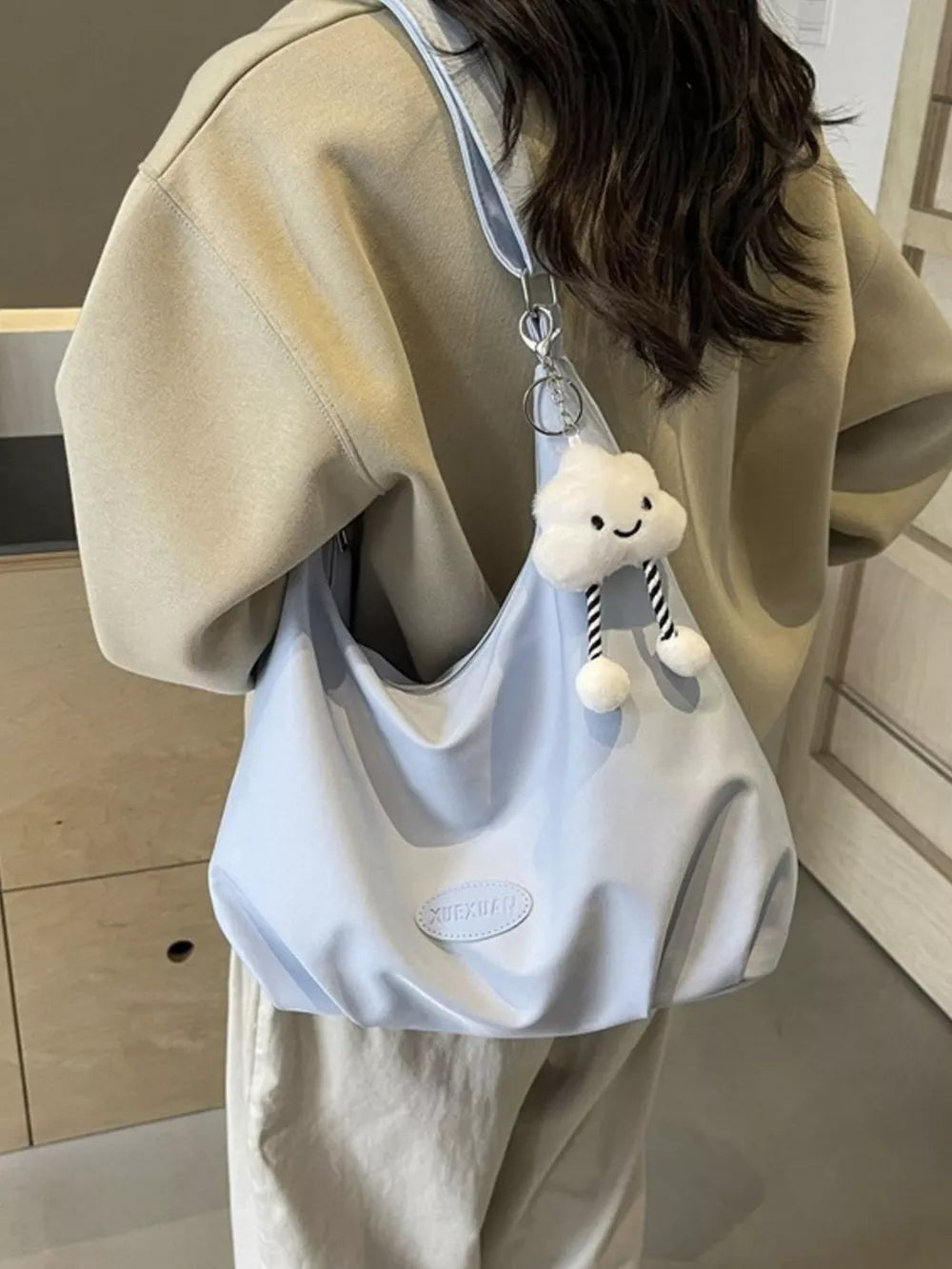 Light blue canvas shoulder bag with cloud charm and adjustable strap.