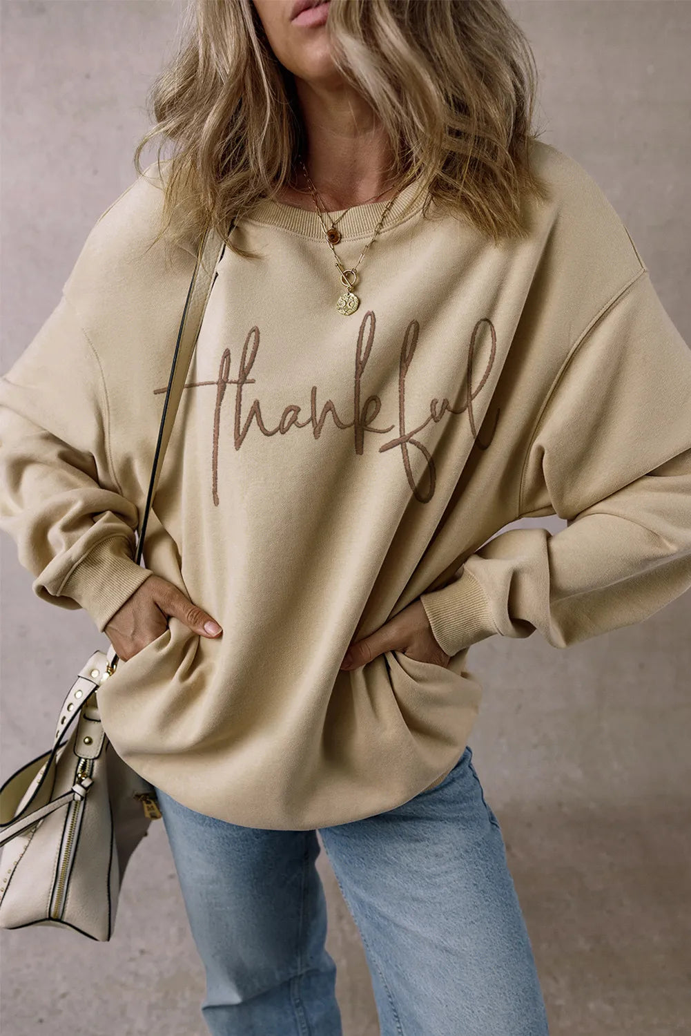 Khaki sweatshirt with "Thankful" script graphic and front pockets, crewneck, long sleeves.