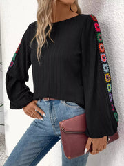Black ribbed shirt with colorful crochet floral sleeve details and balloon sleeves.