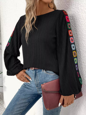 Black ribbed shirt with colorful crochet floral sleeve details and balloon sleeves.