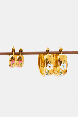 Gold hoop earrings with floral enamel details in pink and white.