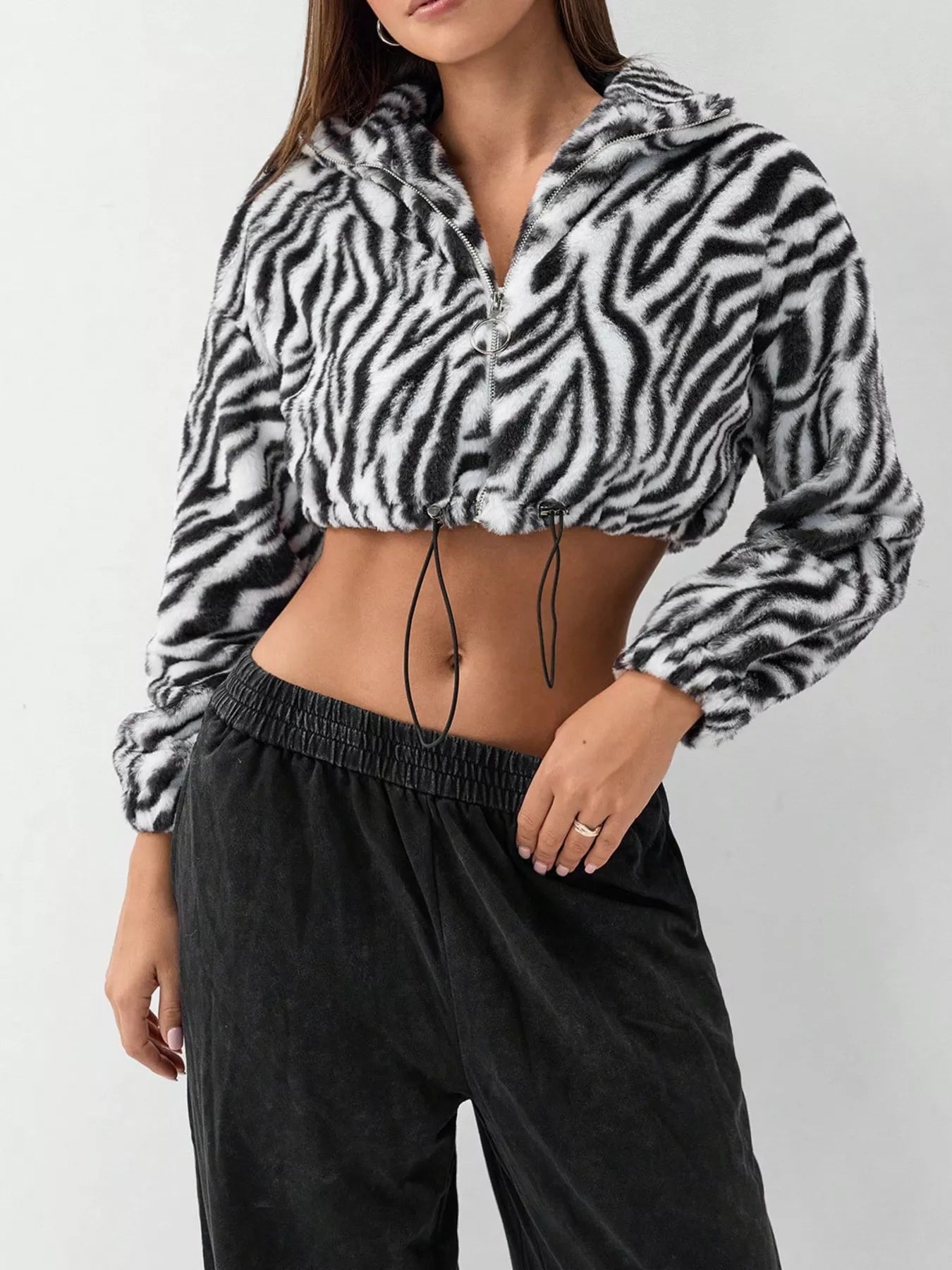 Plush cropped zebra print jacket with drawstring closure and zipper.