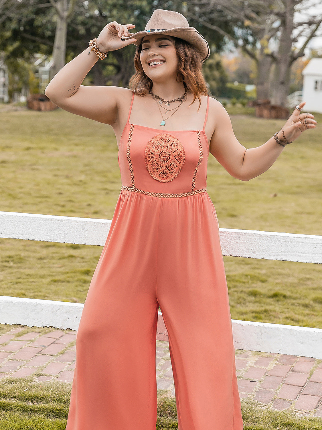 Orange wide leg jumpsuit with embroidered bodice and gold trim detail.