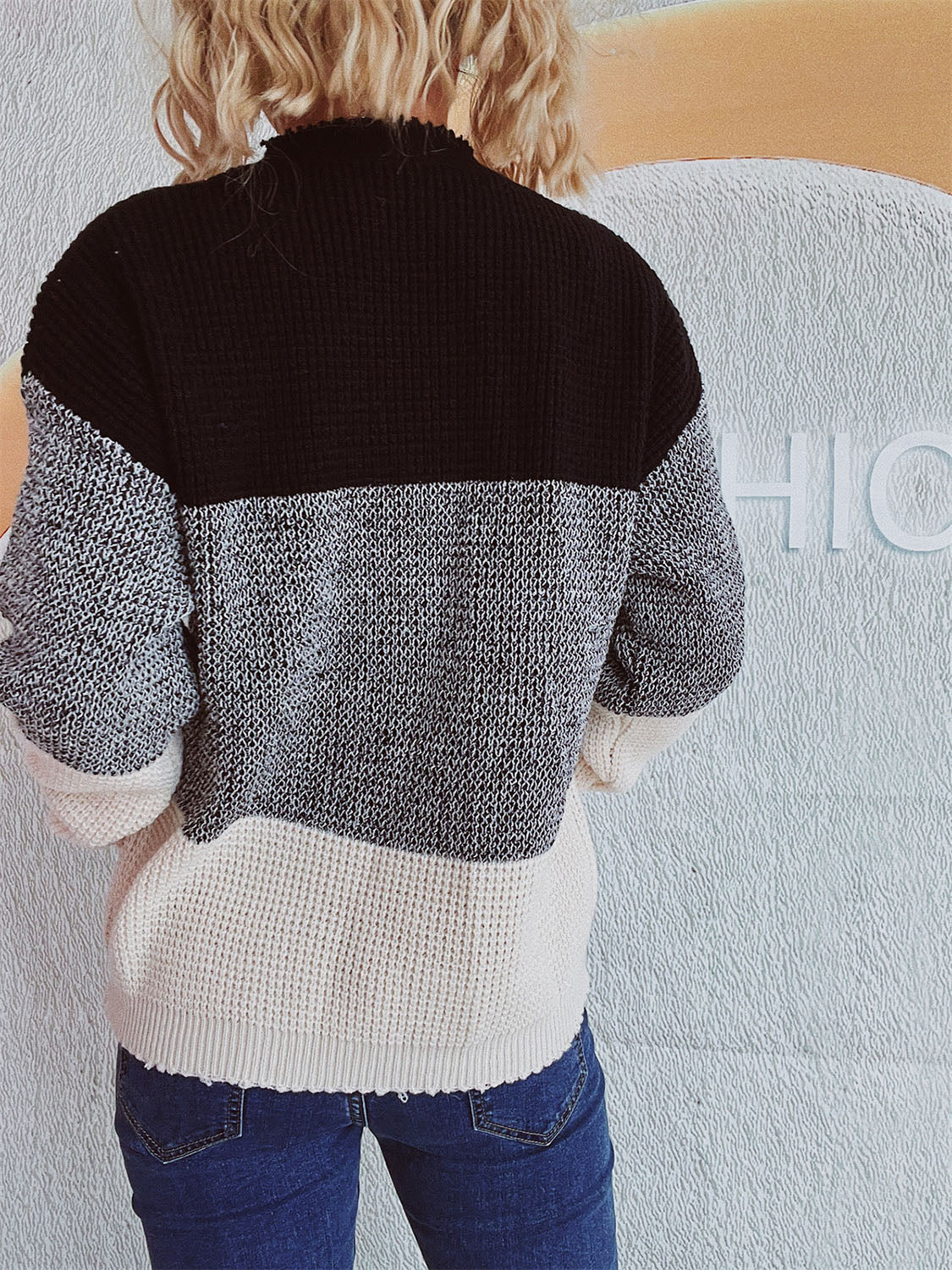 Colorblock knit pullover sweater with black, grey, and cream textured panels.