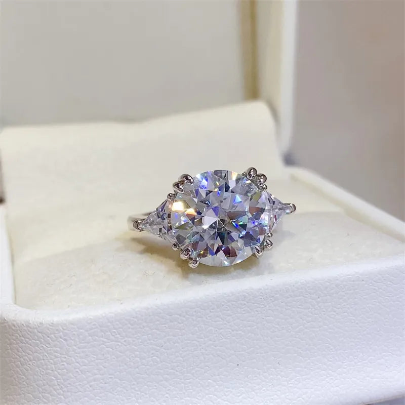 Sterling silver ring with a large round moissanite center stone and two trillion-cut side stones.