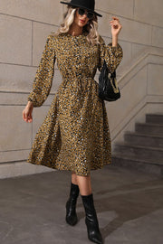 Gathered waist midi dress in olive with animal print, long sleeves, and a tiered skirt.