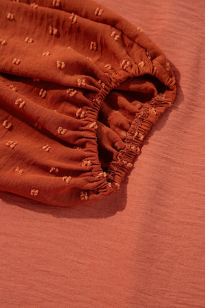 Orange blouson top with Swiss dot textured sleeves and elastic cuffs