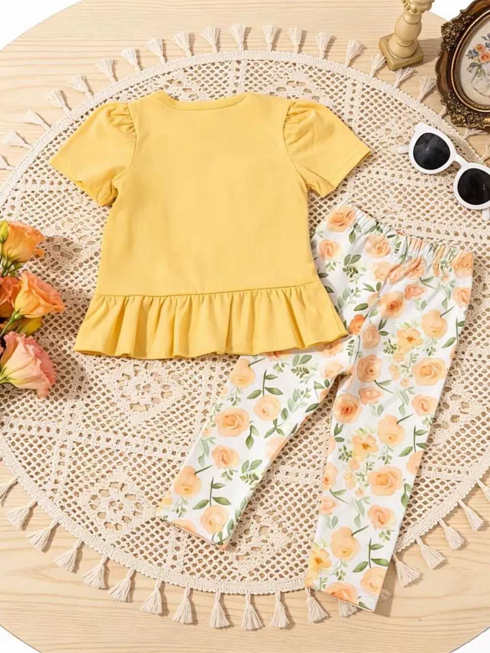Light yellow ruffle top with puff sleeves and floral print leggings.