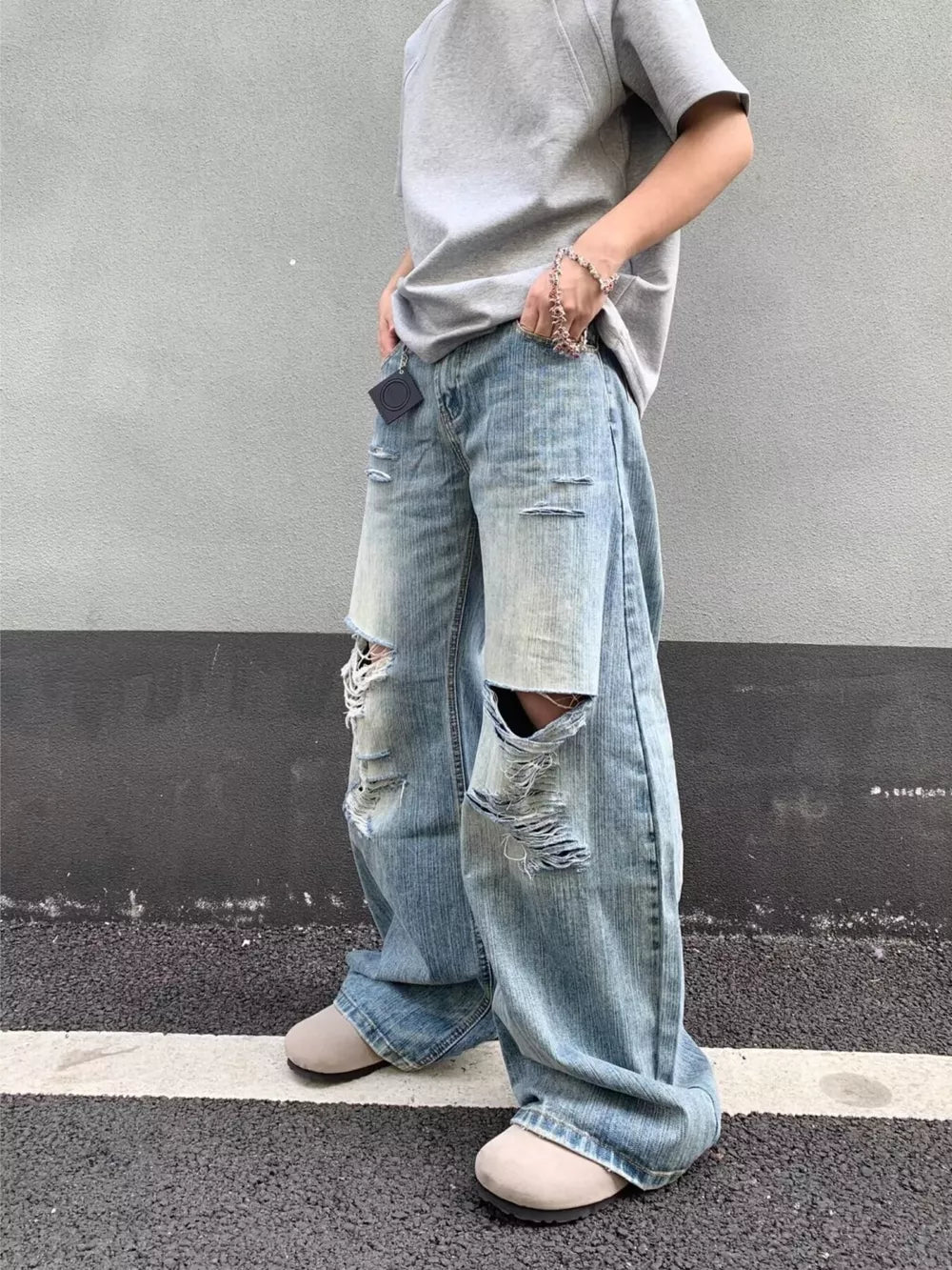 Distressed wide-leg jeans in light wash denim with ripped details and pocket design.