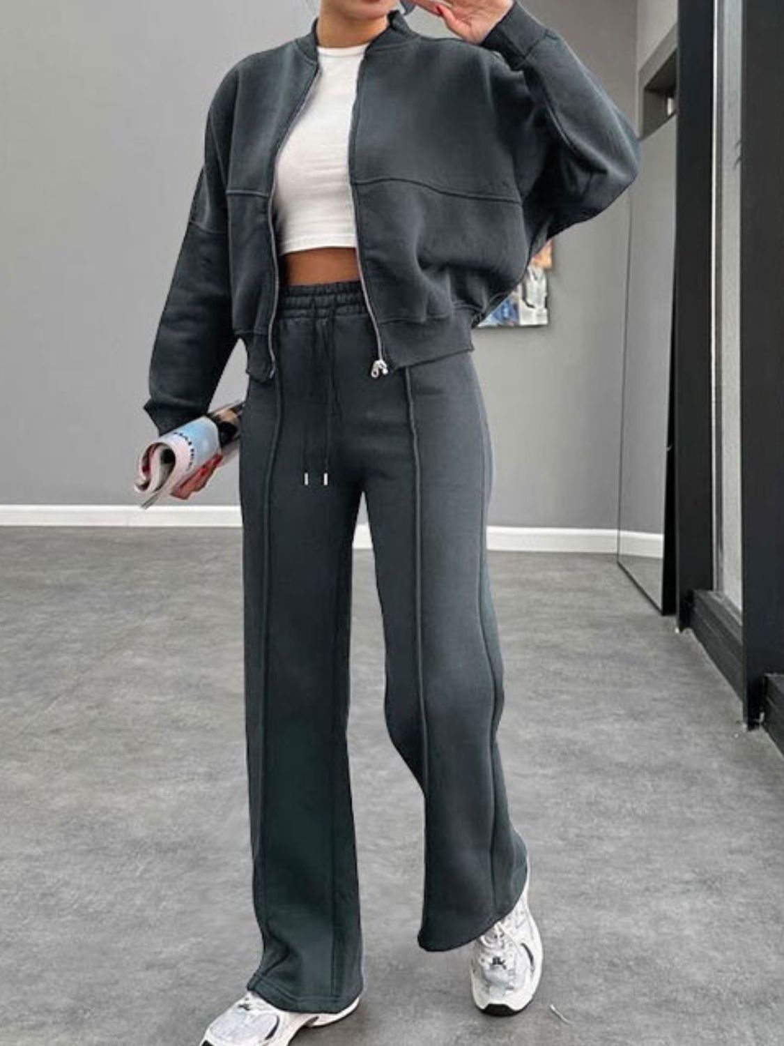 Dark blue bomber jacket and wide-leg tracksuit with drawstring pants and white crop top.