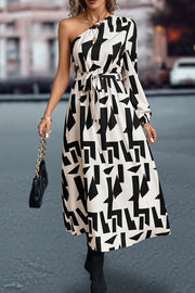 Black and white geometric print asymmetric maxi dress with belt and one long sleeve.
