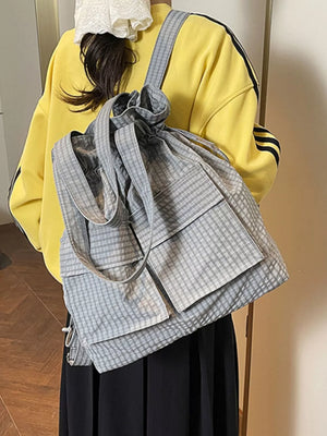 Grey plaid drawstring backpack with dual pockets and adjustable straps.