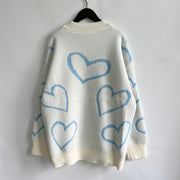 White acrylic knit sweater with pastel blue heart outline pattern and cream ribbed trim.