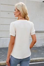 Cream textured V-neck blouse with short puff sleeves and a subtle bow detail.
