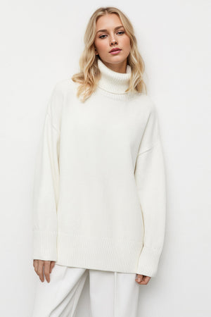 Oversized white turtleneck sweater with ribbed cuffs and hem, relaxed fit.