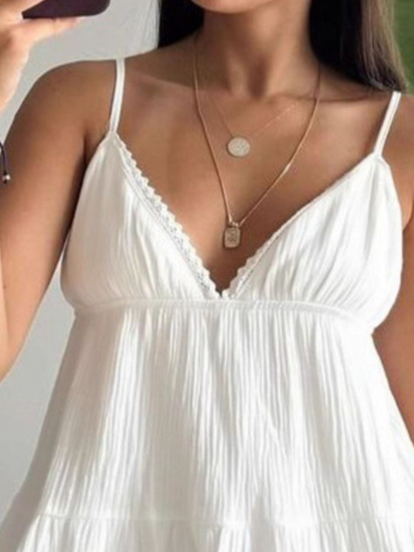 White cotton tiered mini dress with lace trim neckline and spaghetti straps.