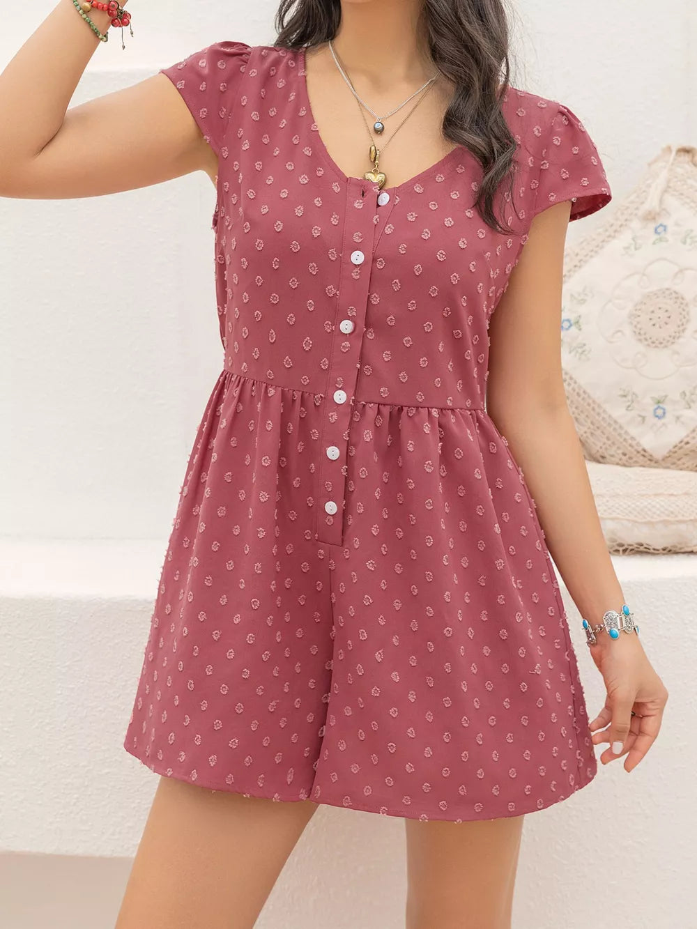 Maternity romper in rose with Swiss dots, cap sleeves, V-neck, and button-down front.
