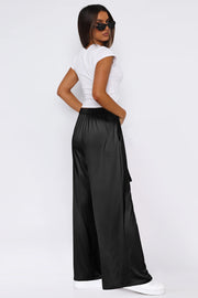 Black satin palazzo trousers with a tie waist and wide legs.