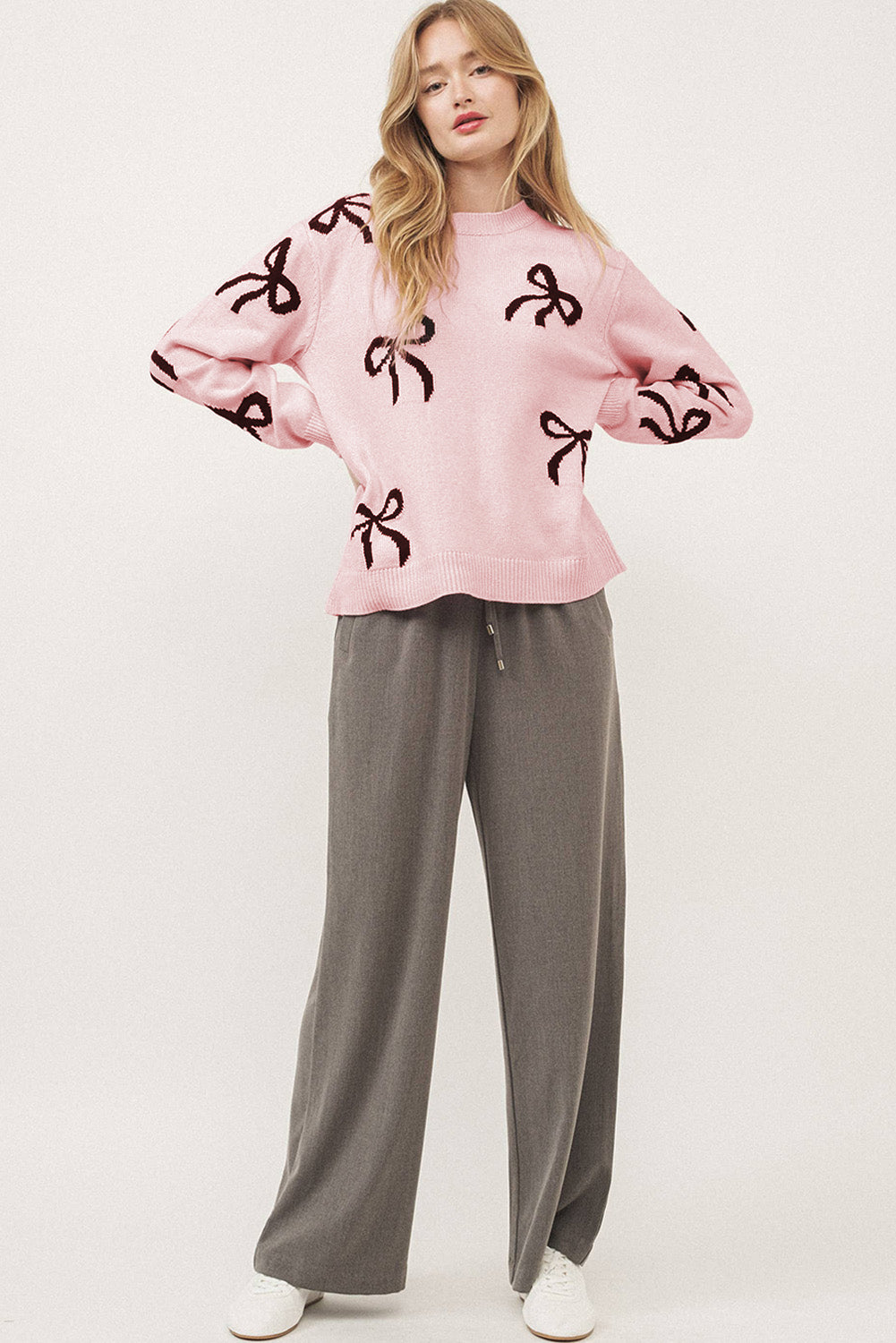 Blush pink knit crewneck sweater with allover dark bow motif pattern.