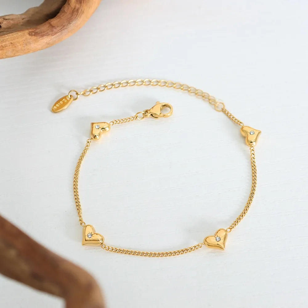 Gold chain bracelet with multiple diamond-accented heart charms.