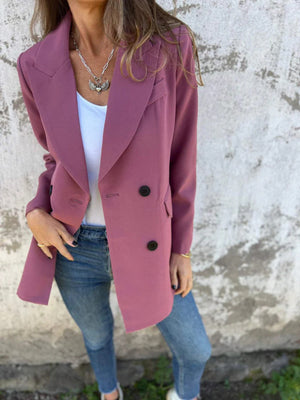 Dusty pink double-breasted blazer with black buttons and sculpted lapels, styled with jeans.