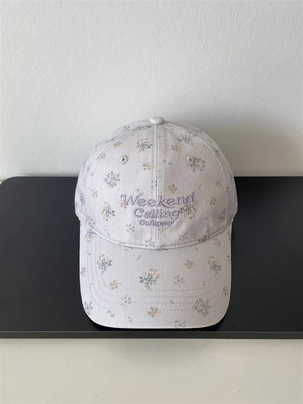 Light gray floral embroidered baseball cap with "Weekend Calling Company" text.